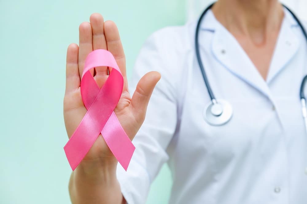 Pink ribbon for breast cancer awareness in doctor's hand, women breast tumor illness campaign. - Poliklinika Medikol Mjesec borbe protiv raka dojke